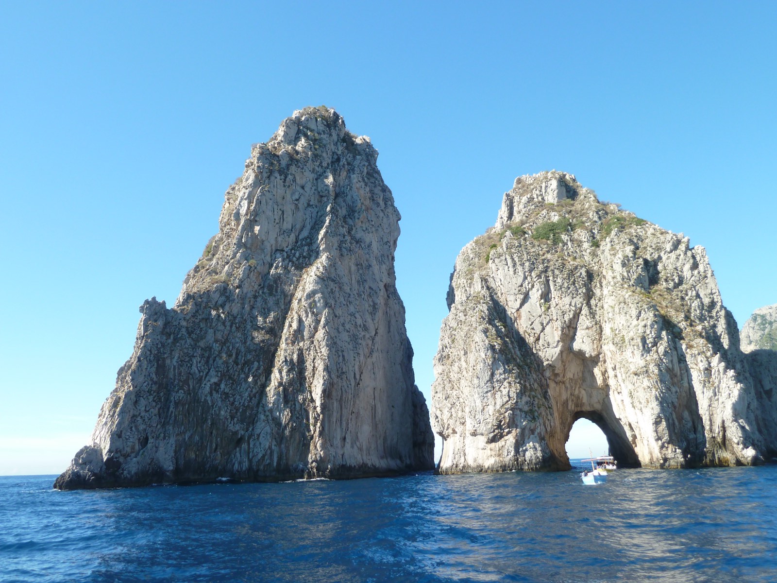 Boat passing the Faraglioni rock arch off Capri